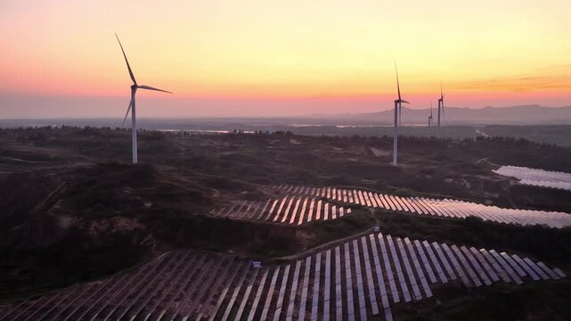 wind turbines and solar panels on a hillside at sunset