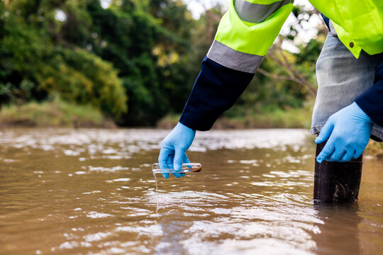 Environmental technician collecting river water and sediment samples for contaminant and heavy metal analysis.