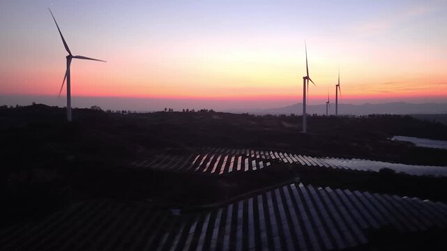 wind turbines and solar panels at sunset