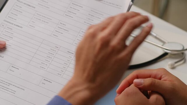 Doctor explaining medical insurance policy document and comforting worried patient at consultation desk