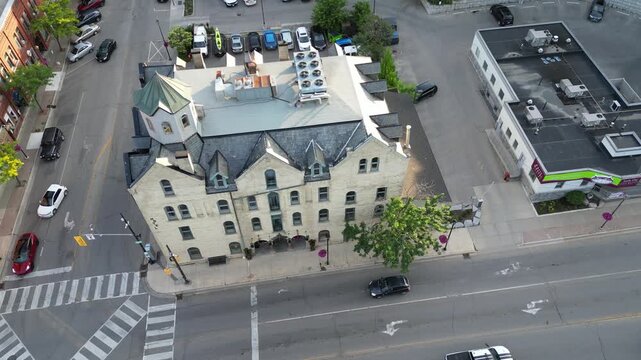 Aerial circular drone shot over a historic hotel, established in 1851, on Grand River Street in downtown Paris, Ontario, Canada on a warm sunny summer afternoon.