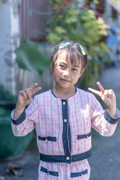 Happy little boy showing thumbs up sign outdoors in a green park, smiling cheerfully and expressing joy, fun, happiness, and positive childhood lifestyle in nature