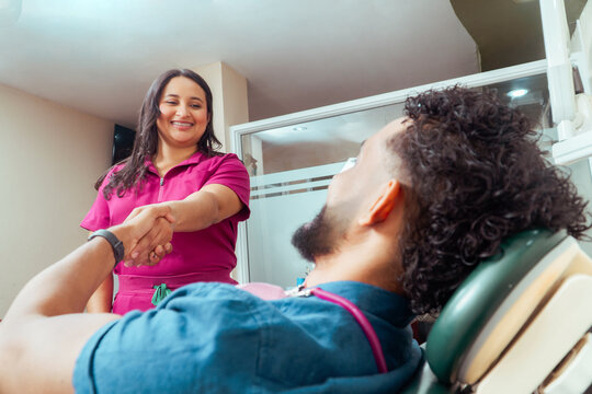 Dentist greeting patient shaking hands in clinic