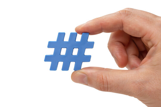 A hand holding a small blue plastic hashtag symbol against a plain white background, for social media, concepts isolated on, a transparent background