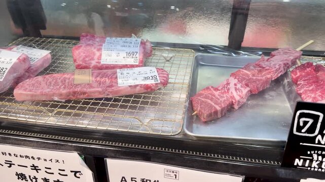 Selection of premium a5 wagyu beef cuts and grilled skewers inside display case at japanese market in kanazawa.