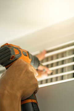worker using electric drill to disassemble central air conditioning vent for cleaning