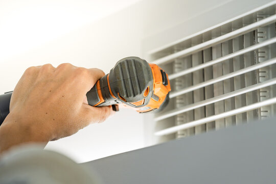 Worker using professional tools to clean central air conditioning vent