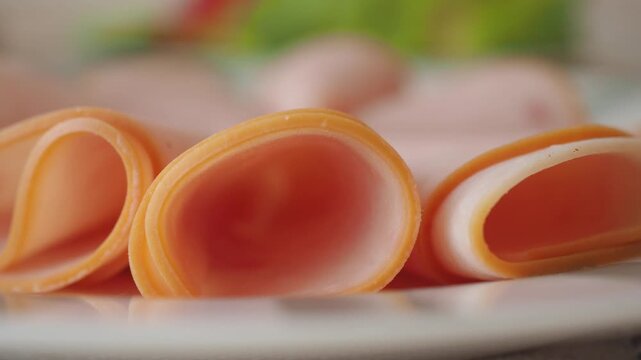 Close up slow motion video of delicious fresh sliced ham on white ceramic plate ready for breakfast or snack