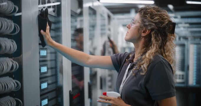 System Technician Cleans Server Rack Glass Doors while Teammate Uses Vacuum Hose to Clear Equipment Dust. Systematic Hardware Cleaning and Facility Management Safeguard Enterprise Network Operations.