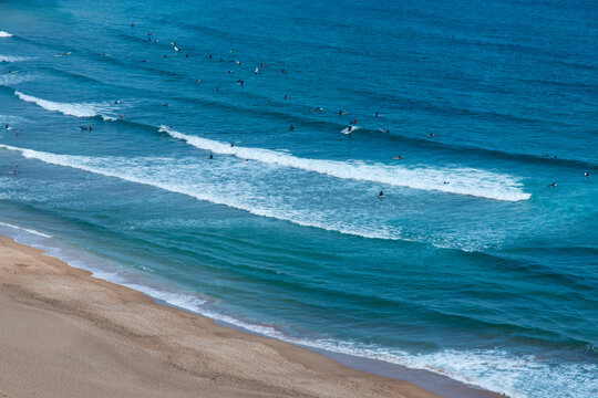 High-Angle View of Surfers Riding Rolling Waves on Sandy Beach