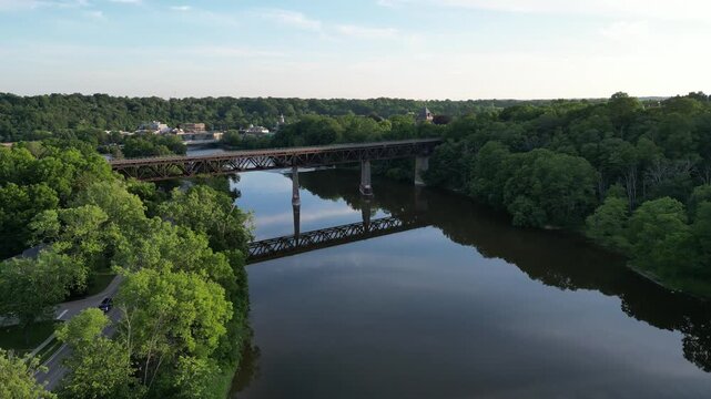 Aerial over the Grand River as it winds through Paris, Ontario, Canada on a warm sunny summer afternoon. Crossing over a railroad train bridge Penman's Dam, towards the William Street Bridge.