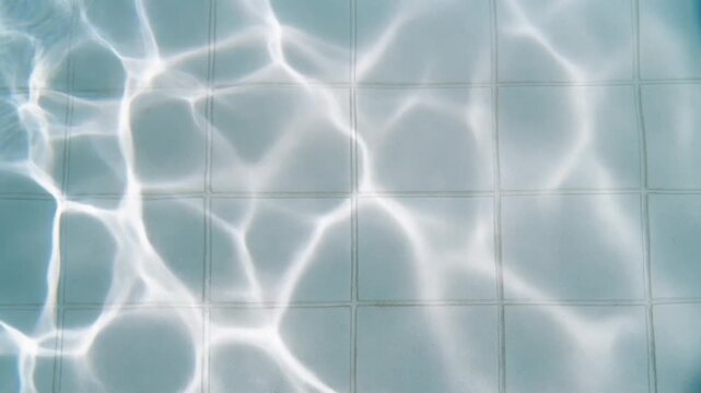 プールの白いタイルの底に広がる光の網がゆっくり揺れる様子