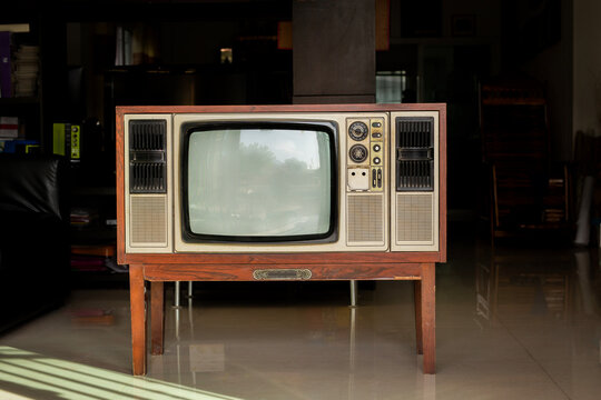 Old-fashioned retro-style television with a blank screen stands in a living room at home. Front view