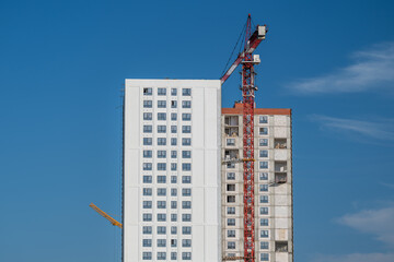 Fototapeta premium Sky-high construction contrasts modern design and raw structure against a brilliant blue sky in a bustling urban landscape