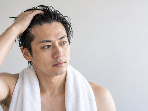 濡れた髪をかき上げて生え際があらわになる男性
