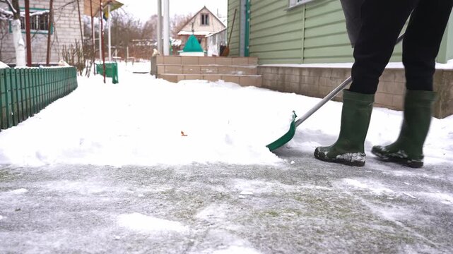Man clears snow from outdoor yard using shovel during winter snowstorm, removing fresh snow from ground while heavy snowfall creates cold seasonal setting and active winter maintenance scene suitable
