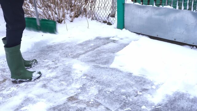 Man clears snow from outdoor yard using shovel during winter snowstorm, removing fresh snow from ground while heavy snowfall creates cold seasonal setting and active winter maintenance scene suitable