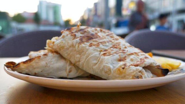 Close up video of two delicious wraps on plate on wooden table in outdoor setting with blurred city street in background
