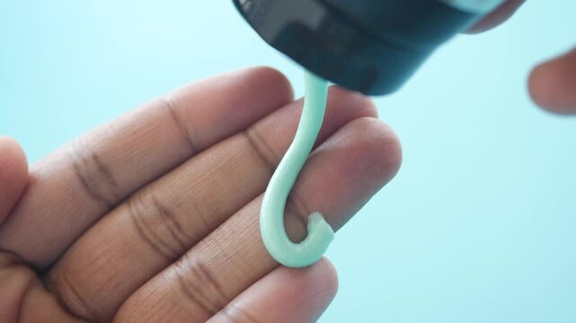 Close-up footage of mint green cosmetic cream being dispensed onto an open palm