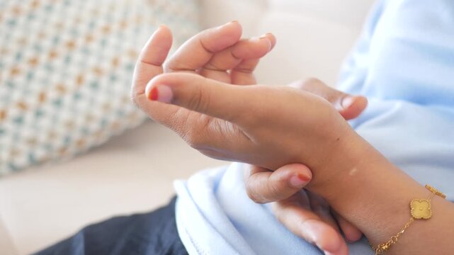 Close up of young woman experiencing pain in her wrist holding her hand and massaging it to relieve discomfort