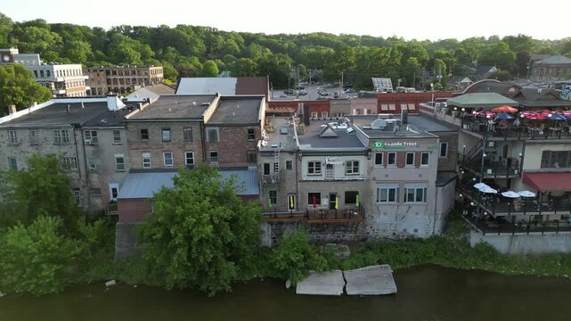 Aerial over the Grand River as it passes through Paris, Ontario, Canada on a summer afternoon. Looking riverside at the buildings of historic downtown Paris along Grand River Street next to the river.
