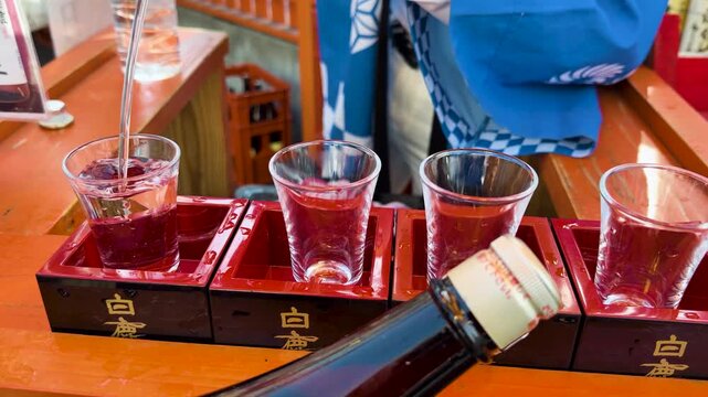 Pouring Japanese sake into small glasses for tasting a traditional cultural experience.