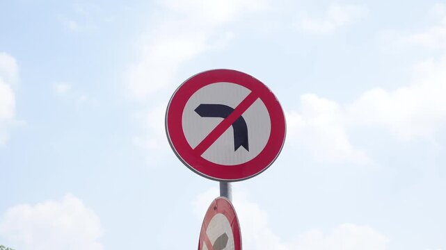 A close up shot of a no right turn sign against a bright blue sky with white clouds, prohibiting vehicles from making right turns