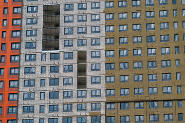 Construction progress on a colorful urban building showing varied textures and a missing section revealing the interior work © beholdereye