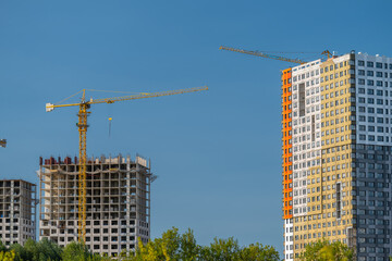 Bright blue skies loom over a bustling construction site with cranes busy at work showcasing a blend of new and old apartment buildings under development © beholdereye