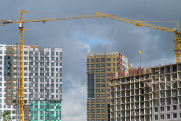 Fototapeta premium Construction progress in a bustling city skyline showcases cranes and new buildings under dramatic clouds