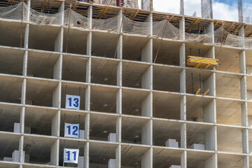 Construction site showcasing the progress of a high-rise building with numbered floors under a clear blue sky © beholdereye