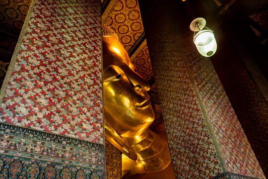 Golden Reclining Buddha face framed by decorated pillars in Wat Pho