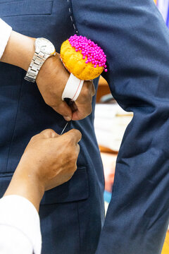 Close-up of professional tailor adjusting and refining new suit with needles to have perfect fit for client in shop before sewing and delivering perfectively fit clothing for client