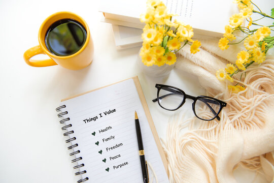 Notebook with things I value inspiring new beginnings and future life planning with yellow cup coffee in worm sunshine.  Goal Life Wellness Concept.