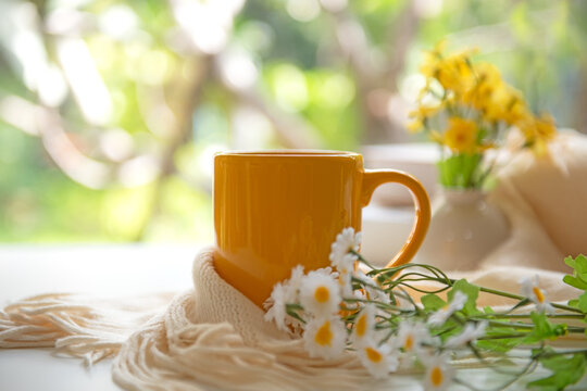 Coffee morning.  Yellow steaming cup of hot coffee for relax after working hobbies crochet on white wooden near window with flowers