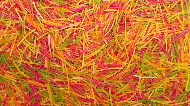 Colorful Vermicelli pasta rotating background. Dry uncooked Seviyan. Multicolored Filini pasta
