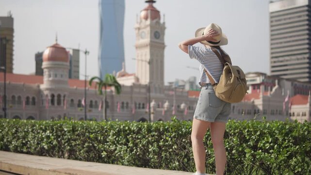 Female tourist in hat with backpack walking in Kuala Lumpur