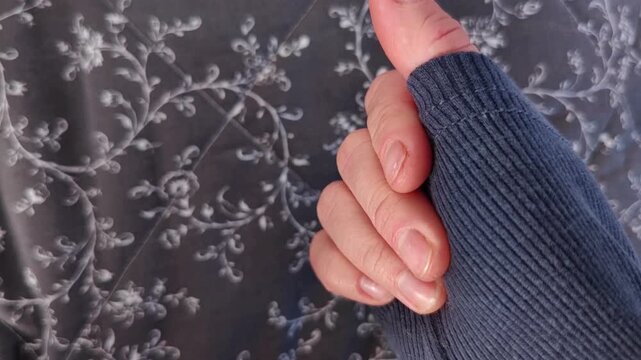 Extreme close-up of woman's hand squeezing a floral patterned sweater sleeve