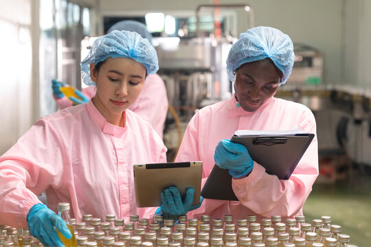 Asian and black factory worker inspect line product with tablet in beverage factory. Food and drinks Industry workers. 