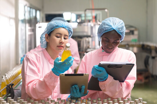 Asian and black factory worker inspect line product with tablet in beverage factory. Food and drinks Industry workers. 