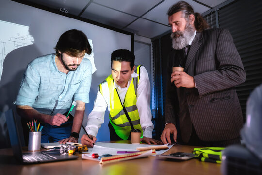 Construction management team discussing building layout paper on desk with senior investor in boardroom. Concept of project planning, schedule of work, brainstorm ideas and find solutions to problems.