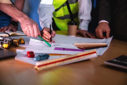 Construction management team discussing building layout paper on desk. Close-up hand while write shot. Concept of project planning, schedule of work, Brainstorm ideas and find solutions to problems.