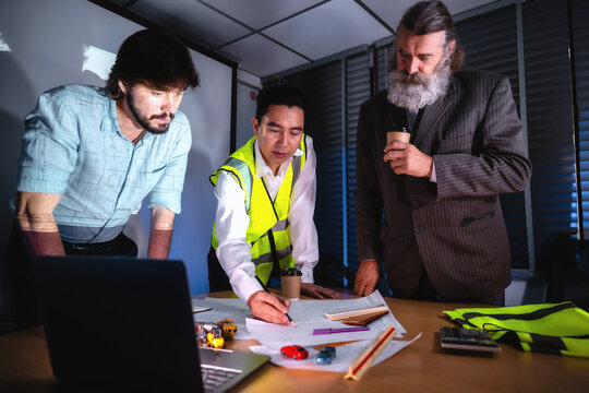 Construction management team discussing building layout paper on desk with senior investor in boardroom. Concept of project planning, schedule of work, brainstorm ideas and find solutions to problems.