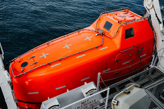 Orange Lifeboat Secured on Davit Launching System of Commercial Vessel
