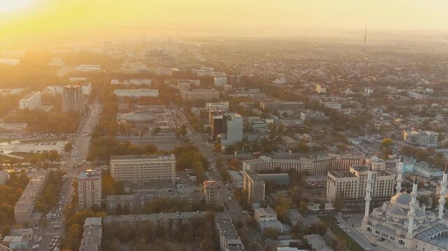 Aerial video of Bishkek downtown at colorful evening light, with illuminated streets, parks, buildings and vibrant Central Asian city life.
