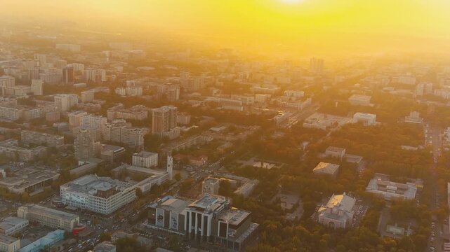 Aerial video of Bishkek downtown at colorful evening light, with illuminated streets, parks, buildings and vibrant Central Asian city life.
