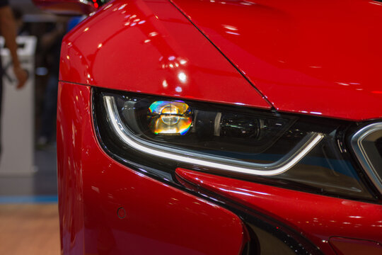 Close view of luxury red car featuring modern LED headlight glossy bodywork showing premium automotive lighting technology design transportation style