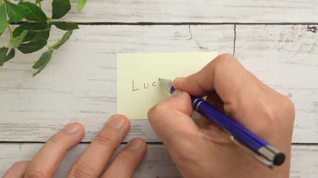 俯瞰撮影で付せん紙にボールペンで「LUCKY」の文字を書く