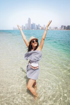 Young caucasian woman enjoy refreshing turquoise water on beach visiting UAE capital Abu Dhabi relax enjoy coastline view - Happy tourist walking sightseeing UAE - Travel and vacation lifestyle