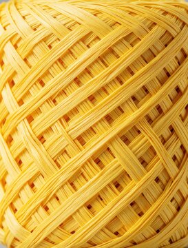 Close up of yellow raffia skein. Eco friendly natural fiber material for handmade craft projects. Bright sunny texture of organic paper straw rolls for DIY decor, weaving, knitting fashion design.